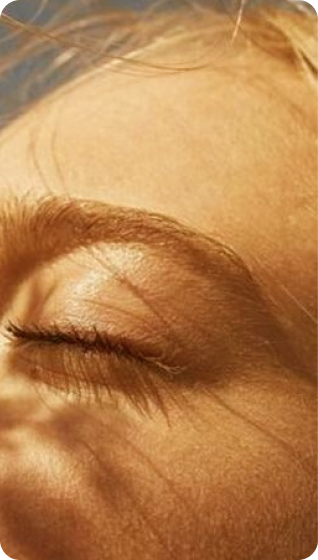 Img (22) Close-up of a woman's face with closed eyes as sunlight gently touches her skin, radiating tranquility.