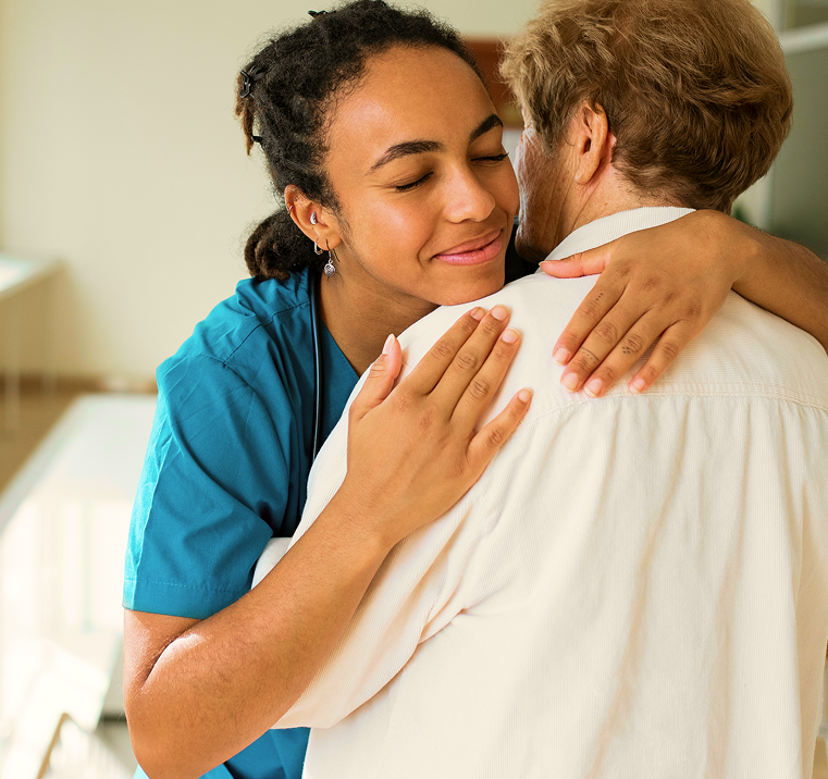 image 32 (1) A nurse hugging an older man, whose thankful facial expression is visible.
