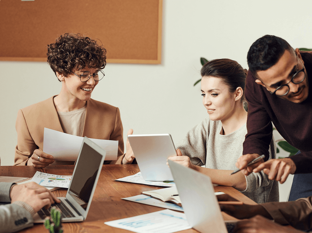 pexels-fauxels-3184360 1 A woman leading a team working together around laptops; three team members—two women and one man—are visible assisting a colleague whose hands and laptop are shown.