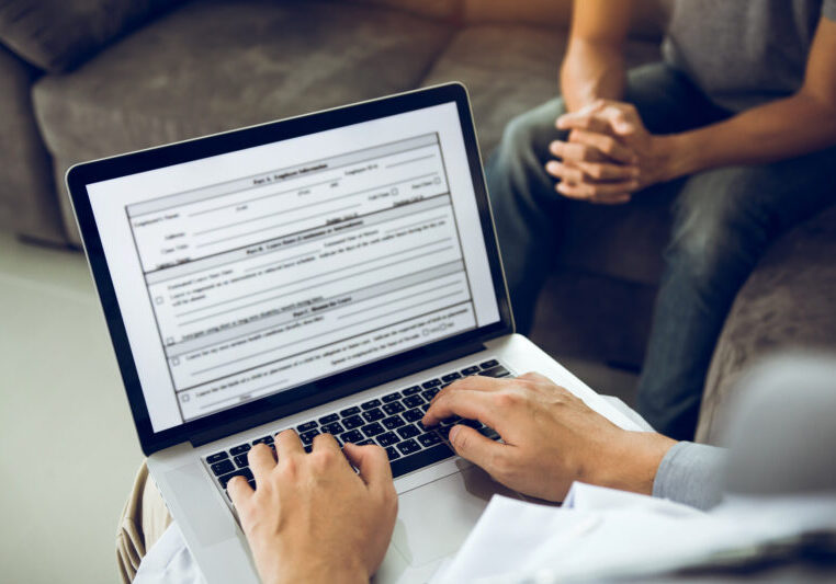 Doctor Is Using A Laptop While Typing The Patient Personal Histo MCO typing up a referral note for transferring a patient to Covenant