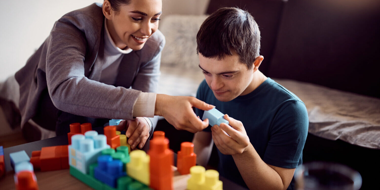 A woman playing a stimulating and educational game with a man with a disability.