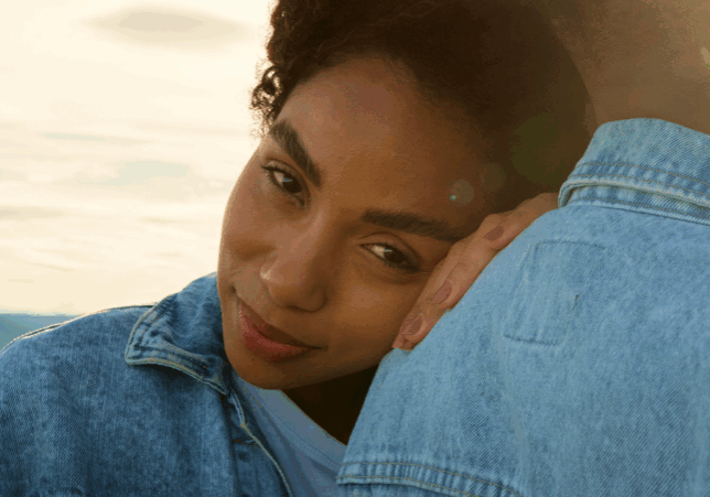 A woman resting on a man’s back as they both look toward the camera.