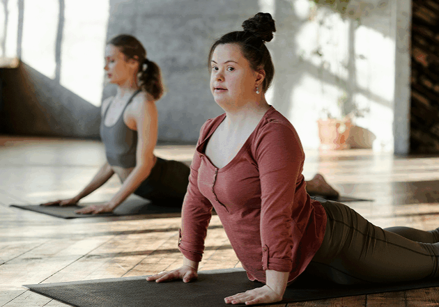 medium-shot-bride-groom-posing-outdoors 1 A woman with Down syndrome and another woman stretching together on an exercise mat.
