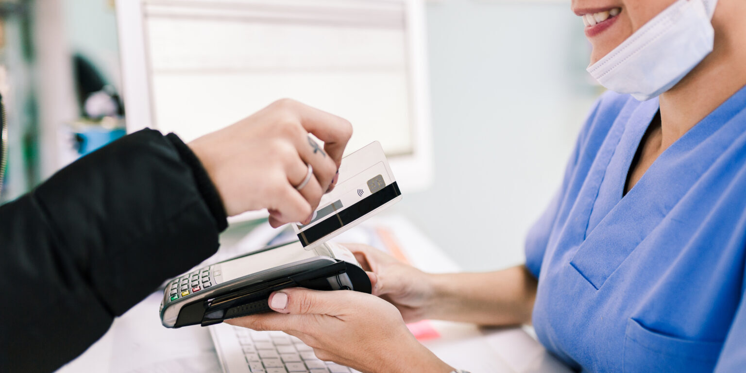 Young woman paying in a veterinary with credit card