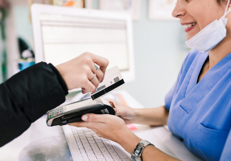 Young woman paying in a veterinary with credit card